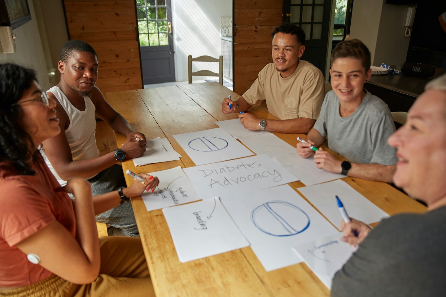Diverse adults collaborate on diabetes advocacy at a sunlit table.